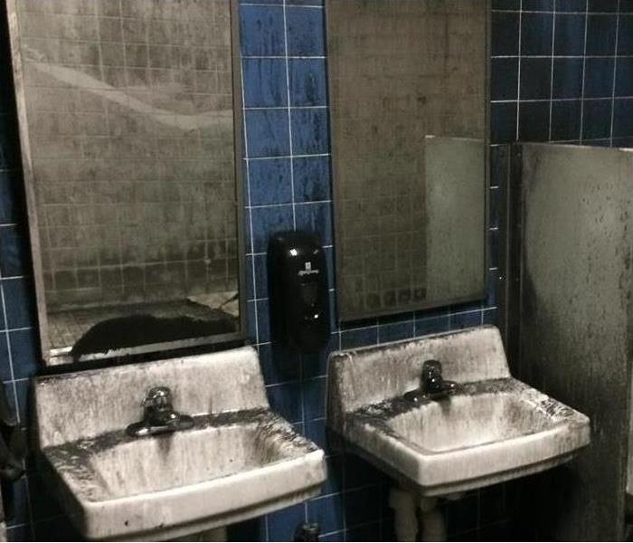 sooty deposits on sinks, walls, mirrors in restroom